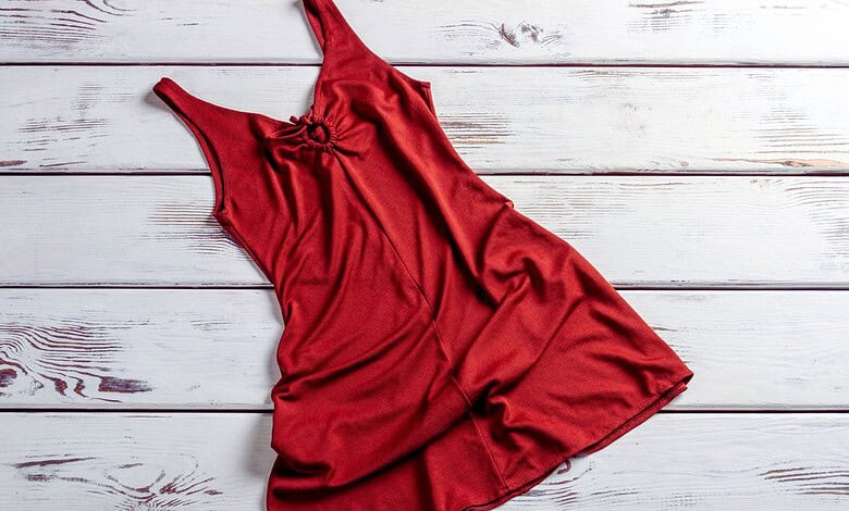 A stylish red dress displayed on a white wooden background, highlighting online dress shopping scams and the importance of secure transactions.