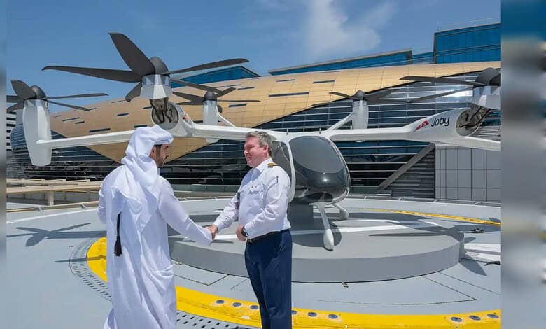 Two men shaking hands in front of a futuristic air taxi at Dubai’s new station.