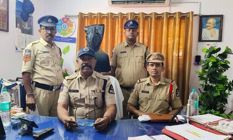 Police officers in uniform posing in an office setting with curtains and framed photographs.