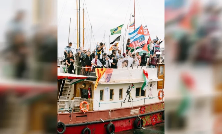 Activists wave flags aboard a flotilla vessel departing Barcelona port