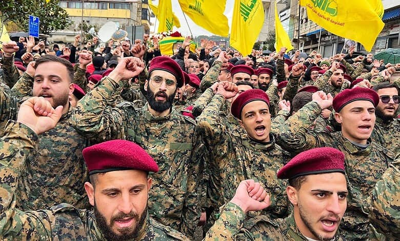 Hezbollah fighters in military uniform and red berets participate in a rally with yellow flags, showing r.