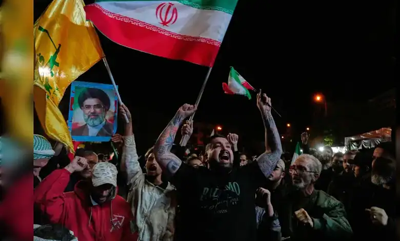 Iranian crowds celebrate ceasefire on April 8, waving national flags and holding a portrait of the Supreme Leader during a nighttime rally in Tehran.
