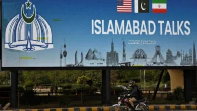 Man on motorbike passes billboard for US-Iran peace talks in Islamabad