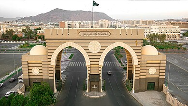 Main entrance gate of the Islamic University of Madinah with city skyline and mountains in the background.