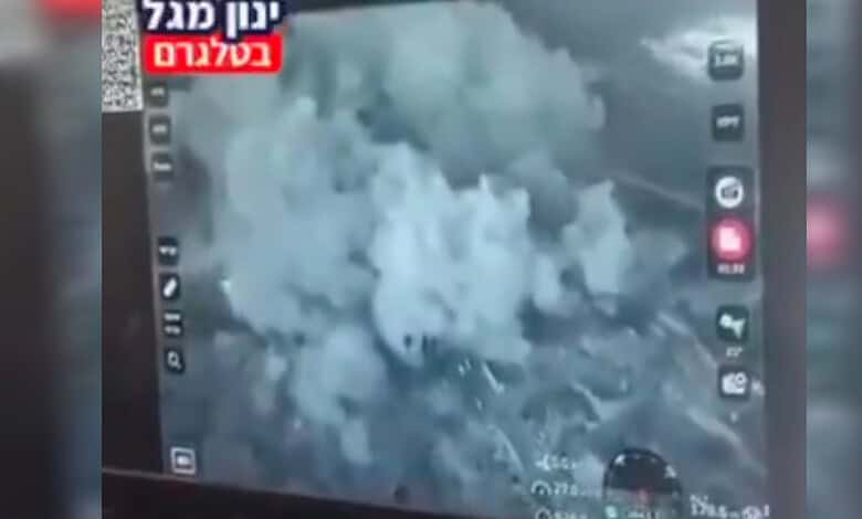 Thick smoke billows over rubble after a building is blown up in southern Lebanon, shown on a screen displaying circulated video footage.
