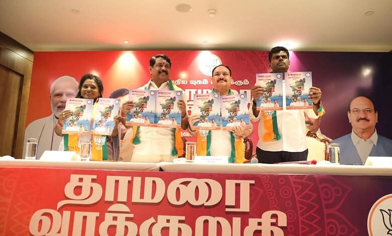 Indian politicians and leaders at a press conference or event, holding newspapers, with a backdrop featuring political symbols and images.