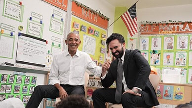 Obama and Mamdani shaking hands in a colourful classroom setting.