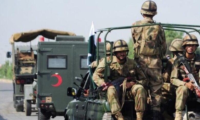 Pakistani army soldiers in uniform seated on a military vehicle during deployment.