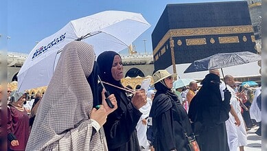 Pilgrims at the Kaaba during summer, with umbrellas for shade, as they perform religious rites in the his.