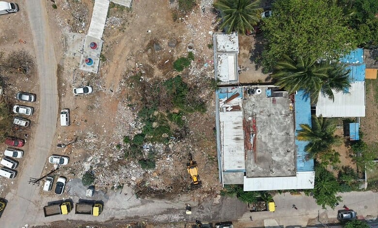 Aerial view of Hydraa removing encroachments around a pond in an urban area. The process involves clearin.