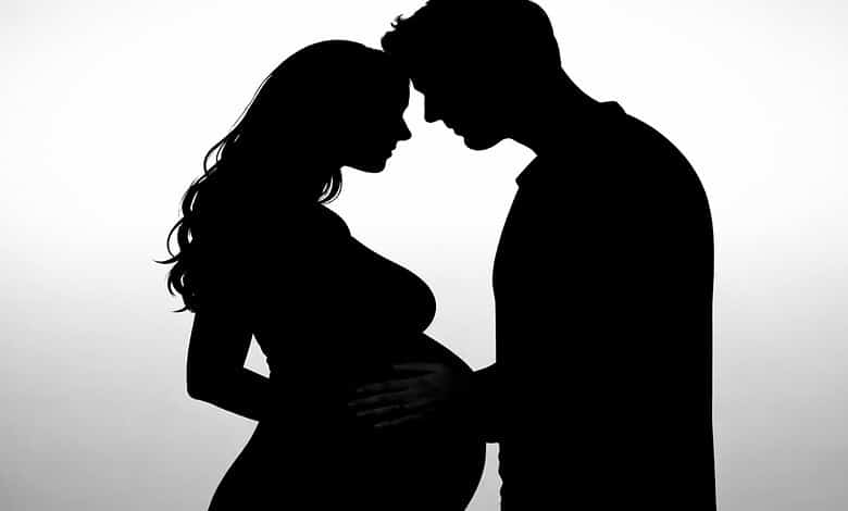 Silhouette of a pregnant Bollywood couple facing each other, highlighting their anticipation of a second.