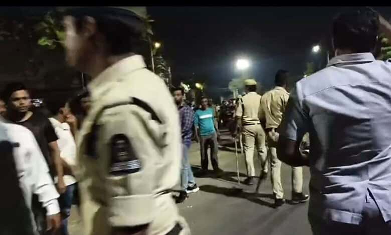Crowd and police presence in Rajendranagar following mosque desecration. Tense atmosphere with residents.