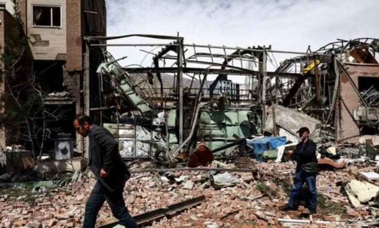 People walk past debris and inspect damage at a destroyed research building at Shahid Beheshti University in Tehran following a strike on April 4, 2026.
