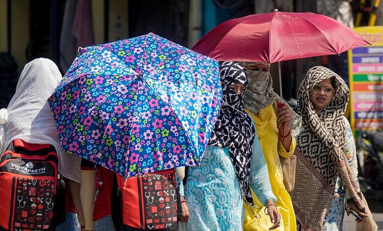 Women with umbrellas walking in a busy street, wearing traditional attire.