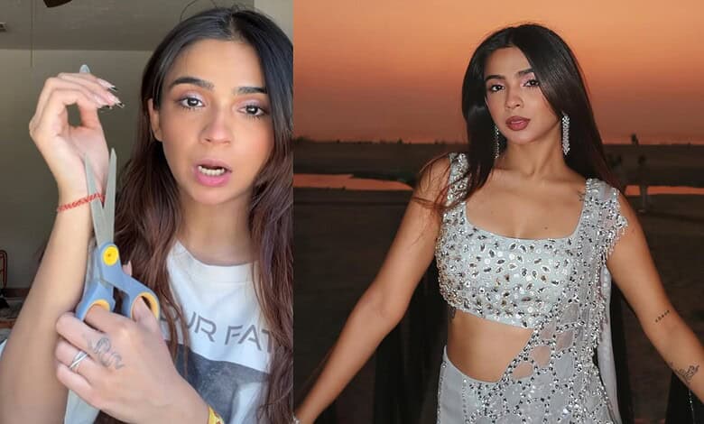 Young woman with long dark hair wearing a silver crop top, posing outdoors at sunset.