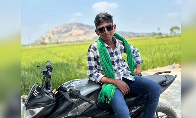 Young boy sitting on a motorcycle in a rural area, with green fields and hills in the background, after a.
