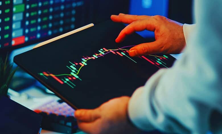A person monitoring stock market data on a tablet, illustrating the dangers of fake trading platforms and financial fraud.