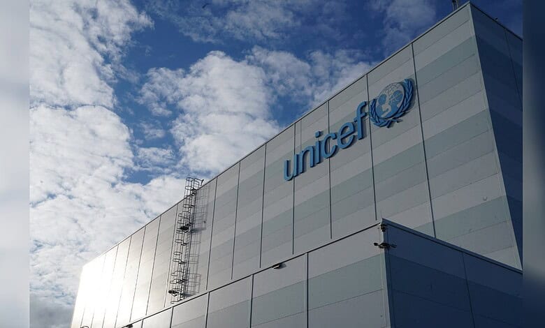UNICEF logo on a modern building facade against a blue sky with clouds.