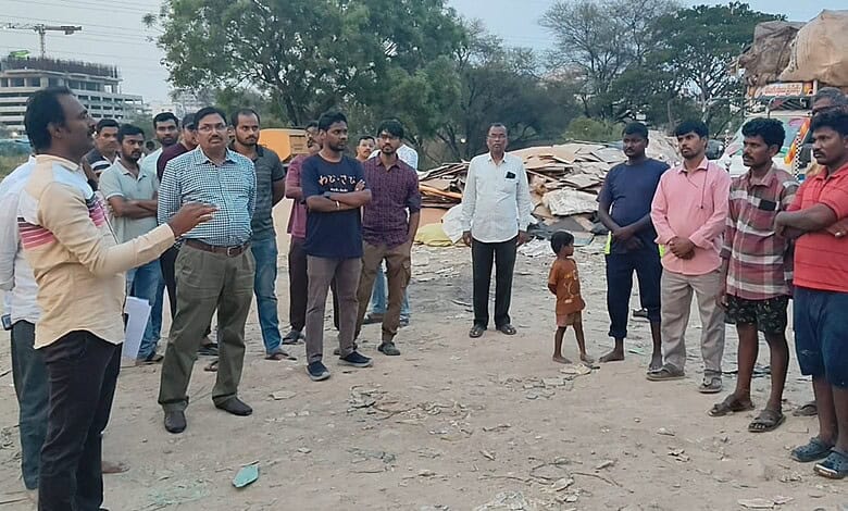 A detailed group of people gathered outdoors, listening to a speaker in a dusty area with scattered debri.