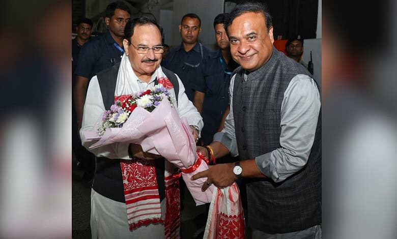 Himanta Biswa Sarma with supporters, holding a bouquet, at a political event in Assam.
