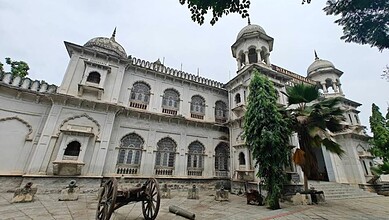 Ancient white palace with domes, arches, and lush greenery, showcasing traditional Indian architecture an.