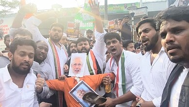 Protesters holding banners and a portrait of Narendra Modi during a rally in India.