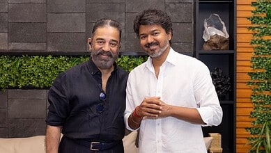 A man in a black shirt and a man in a white shirt smiling together indoors.