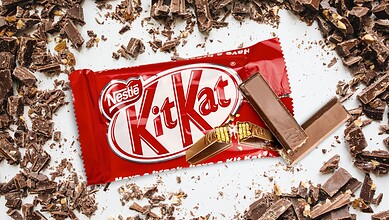 KitKat chocolate bar with broken pieces scattered around, close-up view.