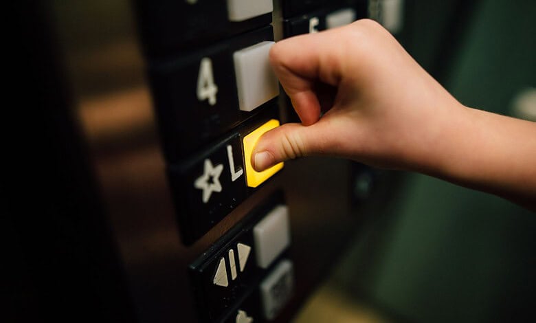 Elevator button being pressed by a child's hand in a residential building.