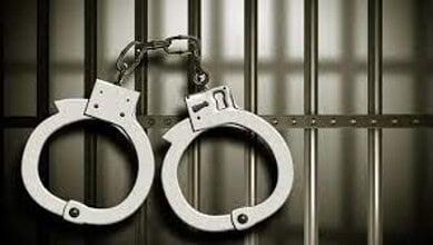 Handcuffs hanging on prison bars symbolising law enforcement and criminal justice.