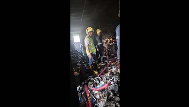 Firefighters inspecting the aftermath of a fire in a building filled with debris and burnt materials. Eme.