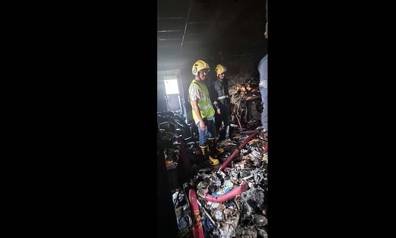 Firefighters inspecting the aftermath of a fire in a building filled with debris and burnt materials. Eme.