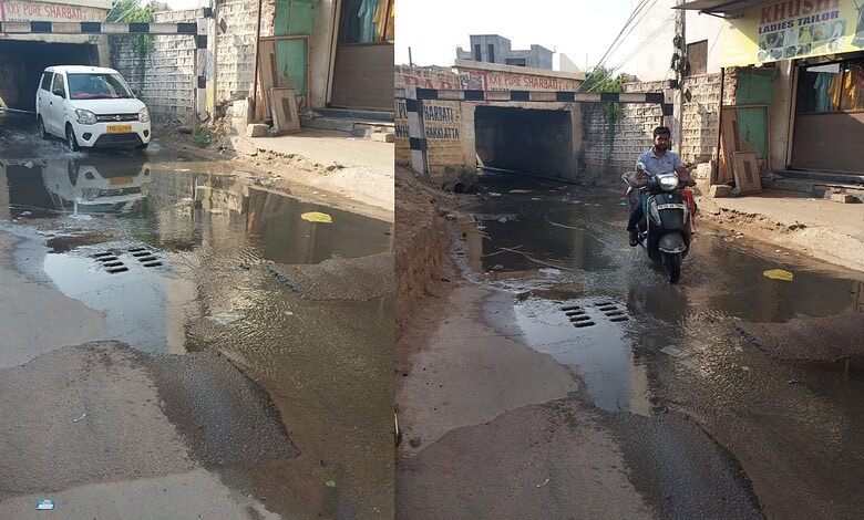 Flooded street with water, a person riding a scooter through a waterlogged area in an urban setting.