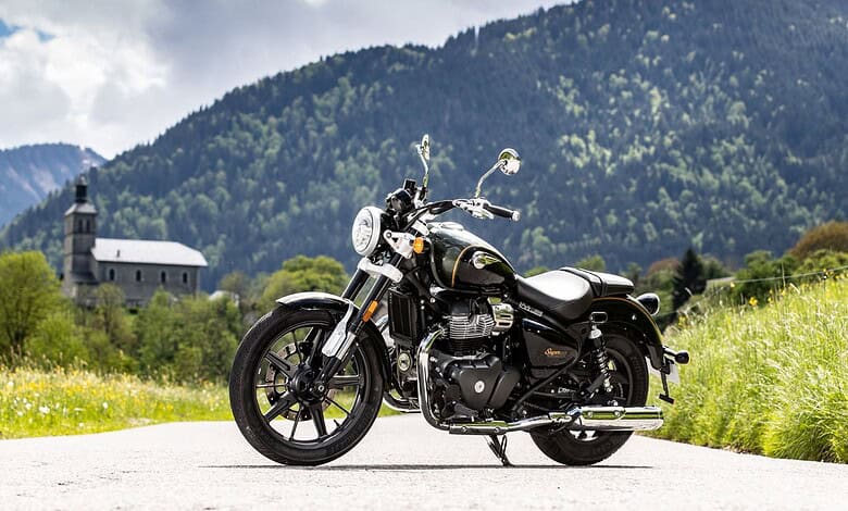 Classic black Royal Enfield motorcycle parked on a mountain road with lush green hills and a church in th.