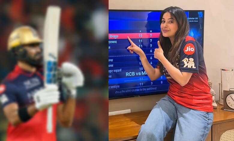 Female cricket player in uniform holding a bat, celebrating a win with a thumbs-up gesture.