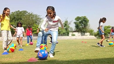 Children playing with colourful balls during summer camp activities outdoors.