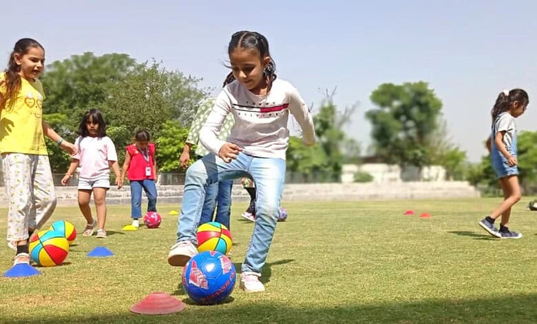 Children playing with colourful balls during summer camp activities outdoors.