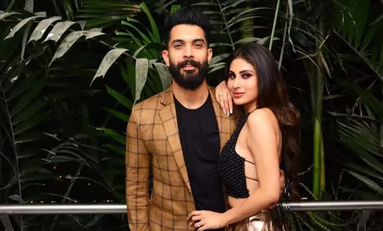 A stylish man and woman posing together at The Siasat Daily event, surrounded by lush green plants.