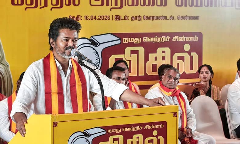TVK leader speaking at Tamil Nadu election rally with supporters, promoting promises of gold and free cyl.