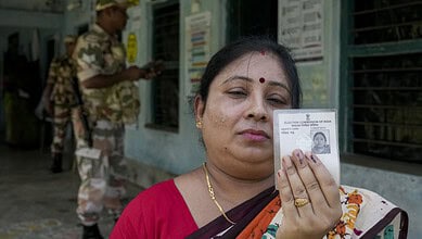 Woman holding voter ID card during Bengal election re-poll at polling station.
