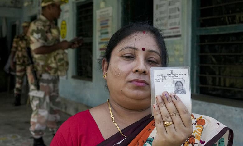 Woman holding voter ID card during Bengal election re-poll at polling station.