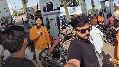 Influencer recording at petrol station with a man in sunglasses and others around, amid claims of threats.