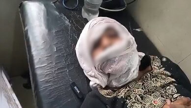 Girl with sindoor on her forehead, lying on a bed, in distress.