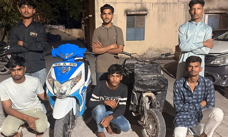 Young men standing with bikes and scooters on a street in Hyderabad, involved in illegal bike stunts.