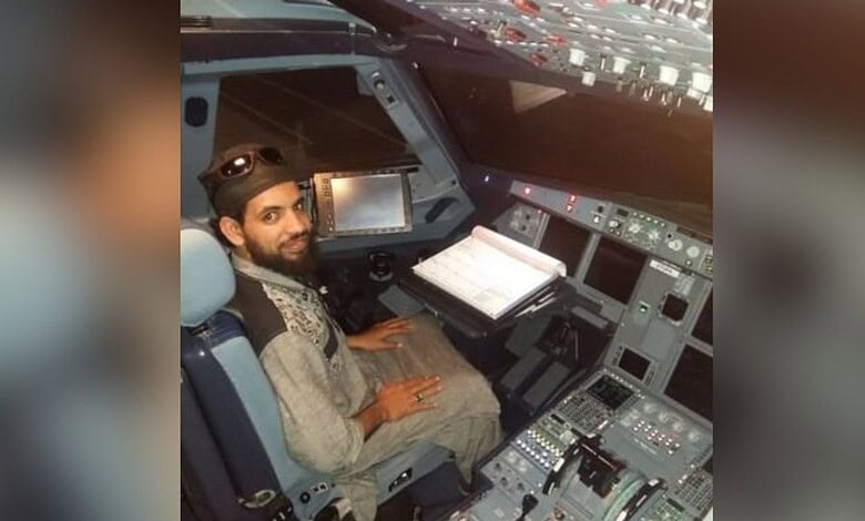 A man sitting in an aircraft cockpit, operating controls and instruments, with a focused expression.