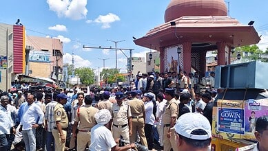 Police and civilians gather around a shrine in a busy urban area during daytime.
