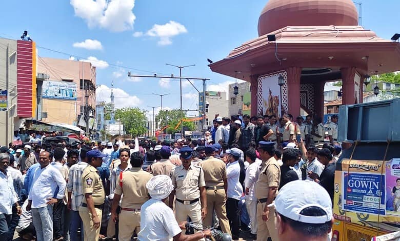 Police and civilians gather around a shrine in a busy urban area during daytime.