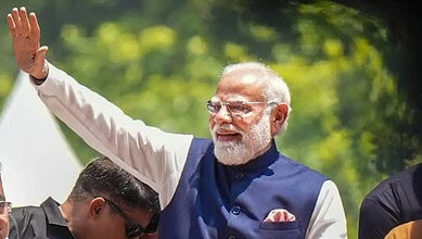 India's Prime Minister Narendra Modi waving to supporters outdoors during a public event.
