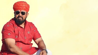 Celebrating Indian culture with a man in traditional red attire and turban, wearing sunglasses, against a.