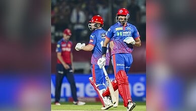 A cricket players celebrating on the field during an IPL match, wearing blue and red uniforms.